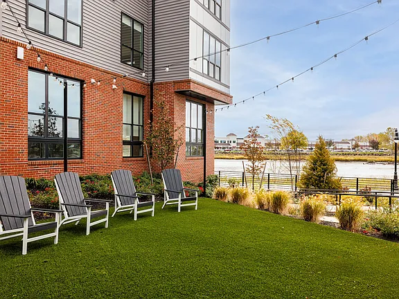 The Breton, multifamily by HH Designers in Bayonne, NJ, waterfront lawn with Adirondack chairs