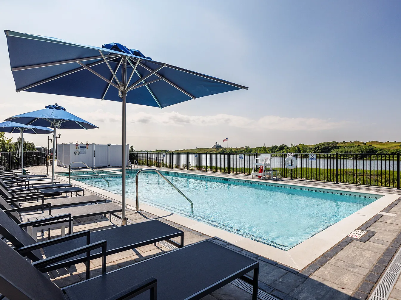 The Breton, multifamily by HH Designers in Bayonne, NJ, pool deck with umbrellas on the water