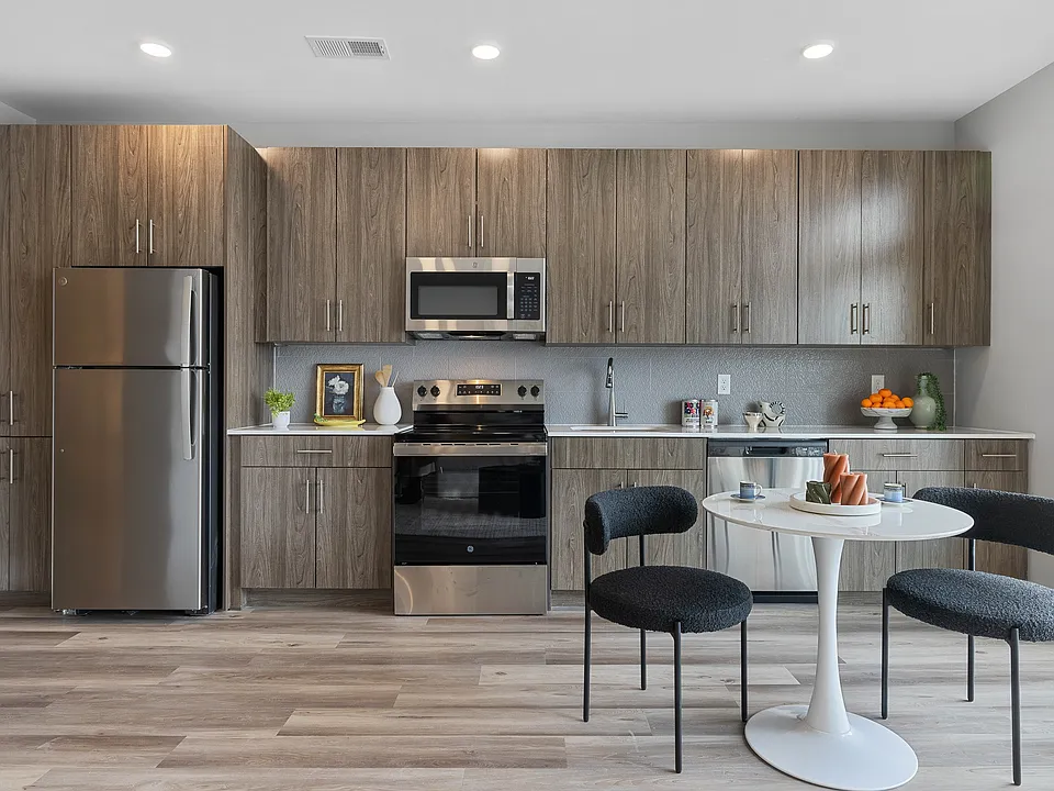 The Breton, multifamily by HH Designers in Bayonne, NJ, kitchen with walnut tone cabinetry and quartz counters