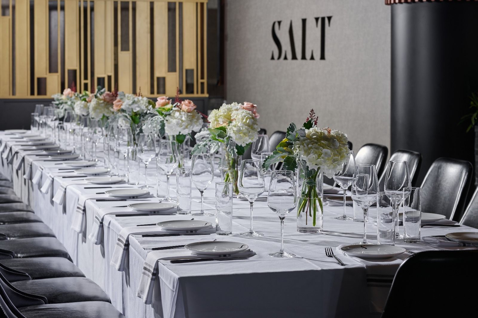 Private event set with a long table beneath the SALT logo wall